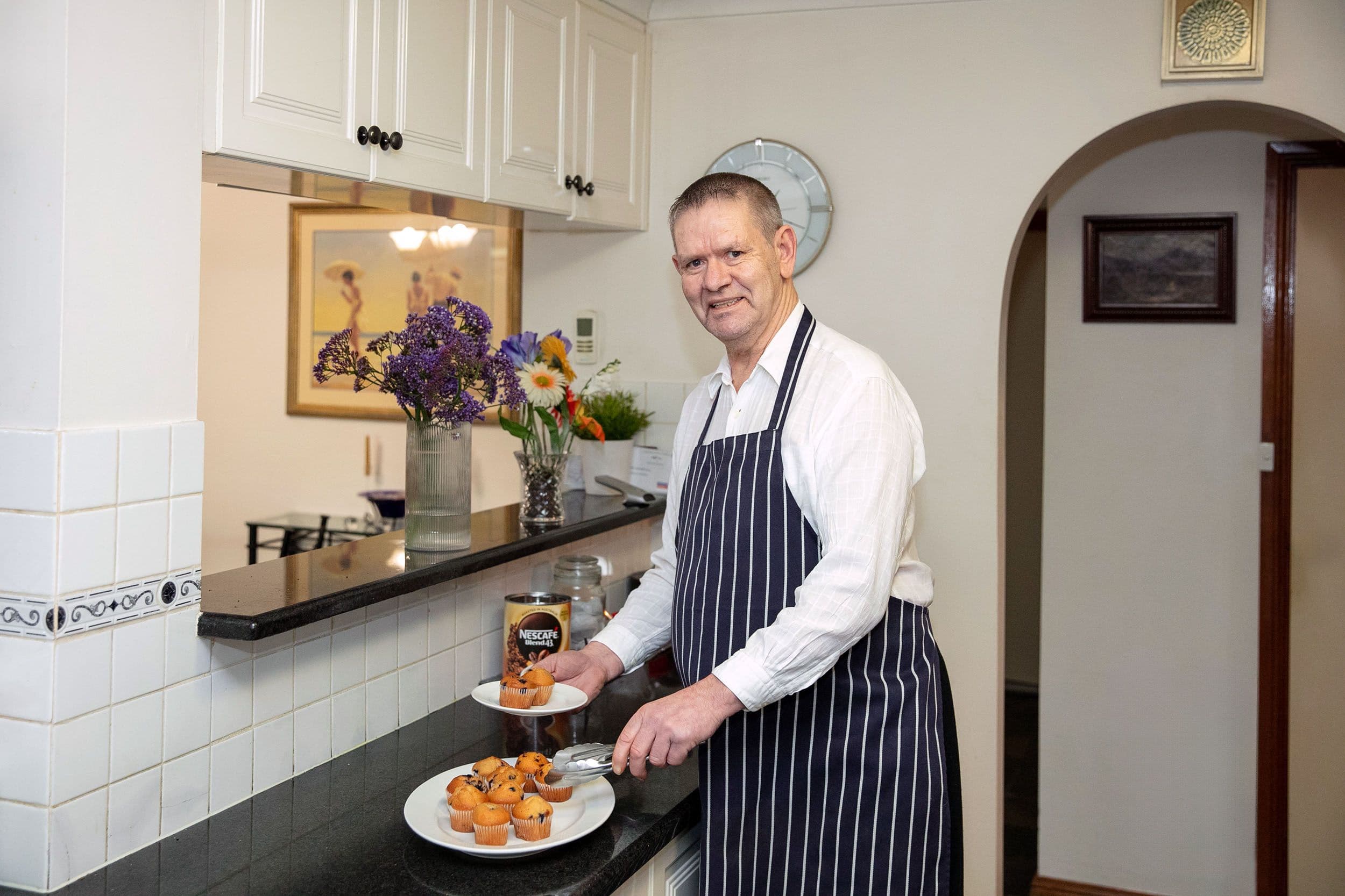 Man cooking and serving muffins at home